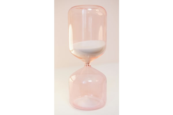 A pink hourglass with white sand in the middle.